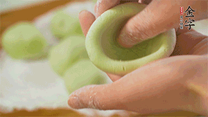 將均分的艾草面團搓成圓，挖一個窩，放入餡心，再搓成圓。