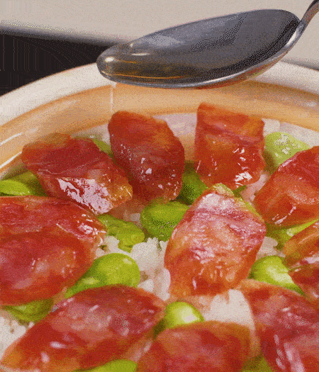 大米出現(xiàn)小孔時(shí)開蓋放香腸，往鍋邊淋入少許油，再燜煮8~10分鐘左右。